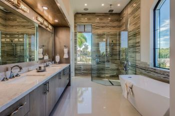 Modern bathroom with double vanity, walk-in shower, freestanding tub, and large windows with natural light