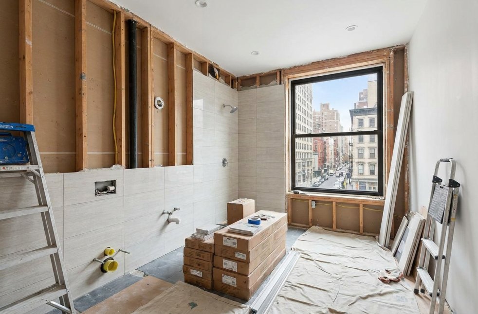Bathroom remodel in progress in a Manhattan apartment with new tile and exposed walls