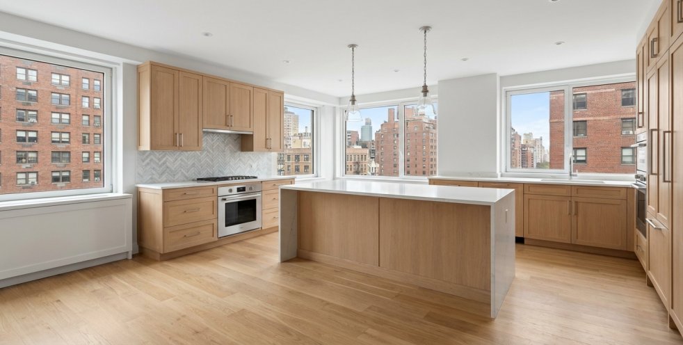 Remodeled Manhattan apartment kitchen with light wood cabinets, island, and city views